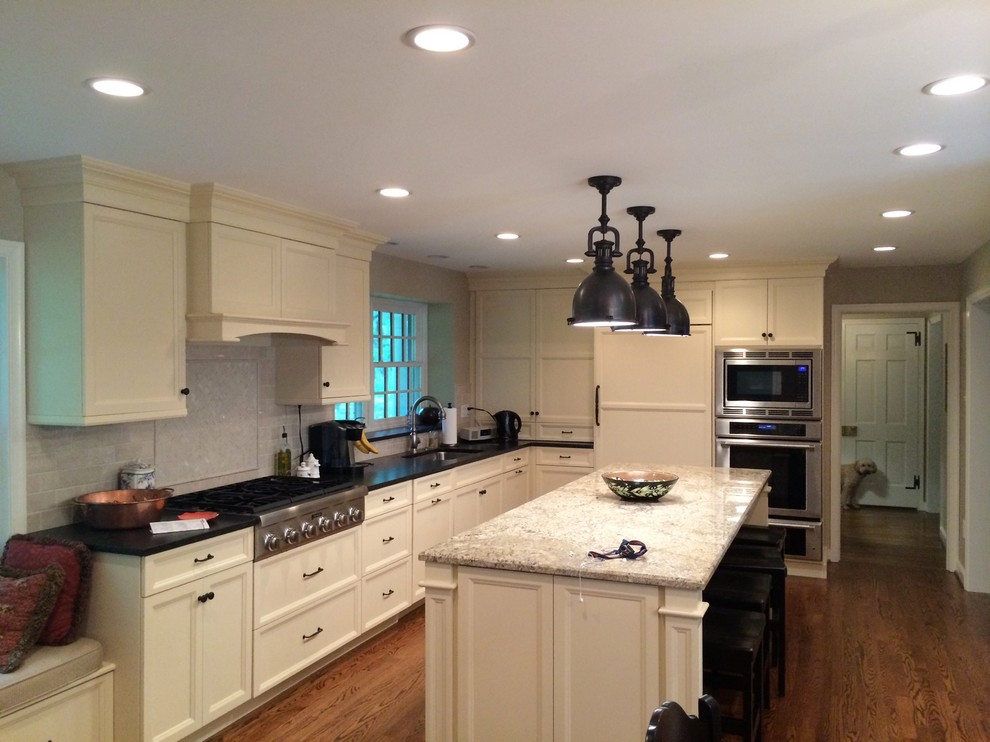 Eat-in kitchen - mid-sized transitional l-shaped medium tone wood floor eat-in kitchen idea in Philadelphia with an undermount sink, recessed-panel cabinets, white cabinets, quartz countertops, white backsplash, subway tile backsplash, stainless steel appliances and an island