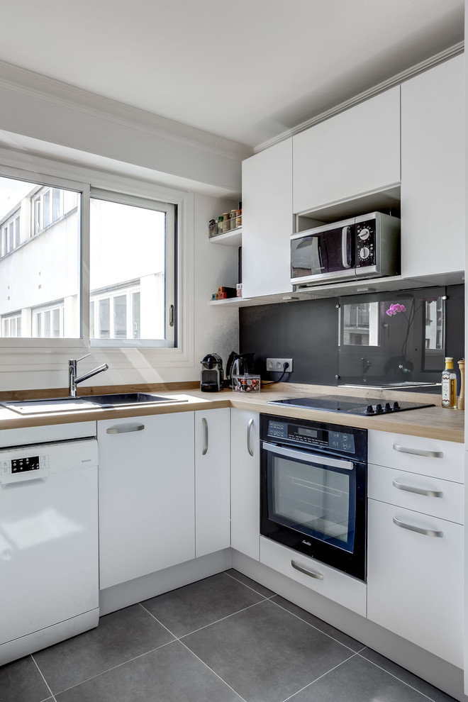 This is an example of a mid-sized contemporary u-shaped separate kitchen in Paris with a single-bowl sink, beaded inset cabinets, stainless steel cabinets, wood benchtops, stainless steel appliances, cement tiles, with island and grey floor.