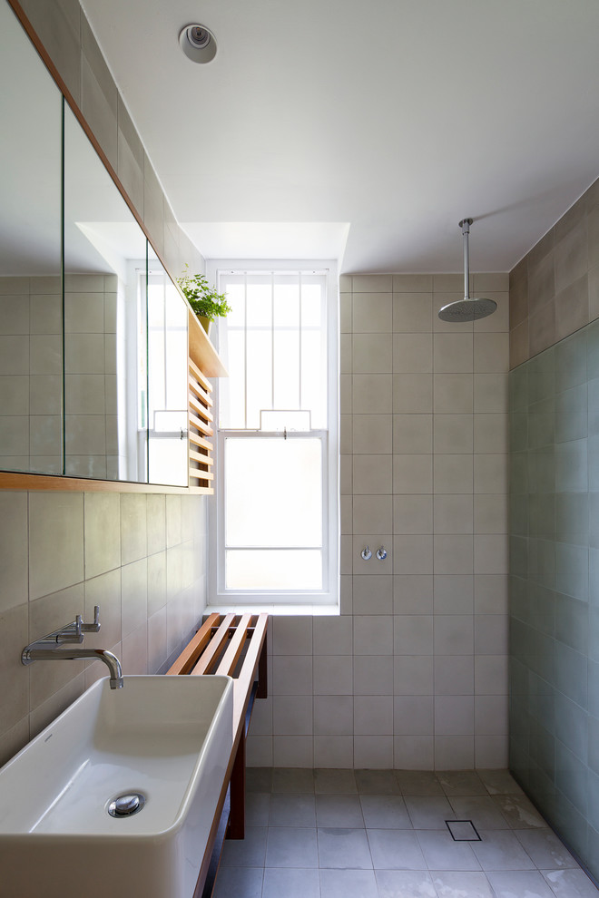 This is an example of a contemporary wet room bathroom in Sydney with open cabinets, medium wood cabinets, beige tile, gray tile, cement tile, grey walls, cement tiles, a vessel sink, wood benchtops, grey floor, an open shower and brown benchtops.