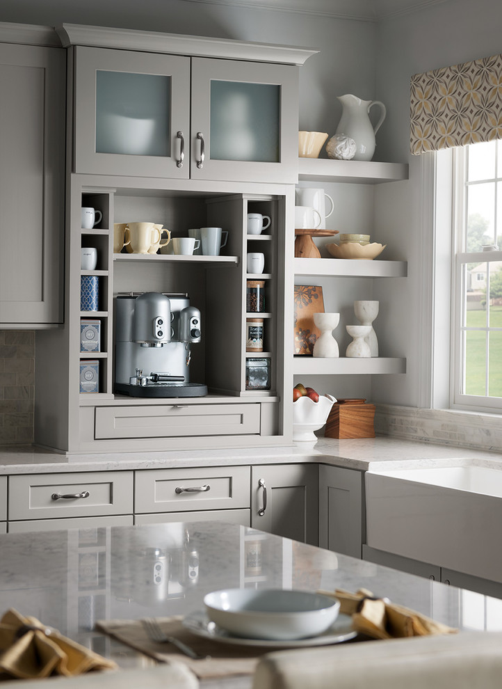 Example of a kitchen design in DC Metro with a farmhouse sink, shaker cabinets, gray cabinets, quartz countertops, gray backsplash, stone tile backsplash, stainless steel appliances and an island