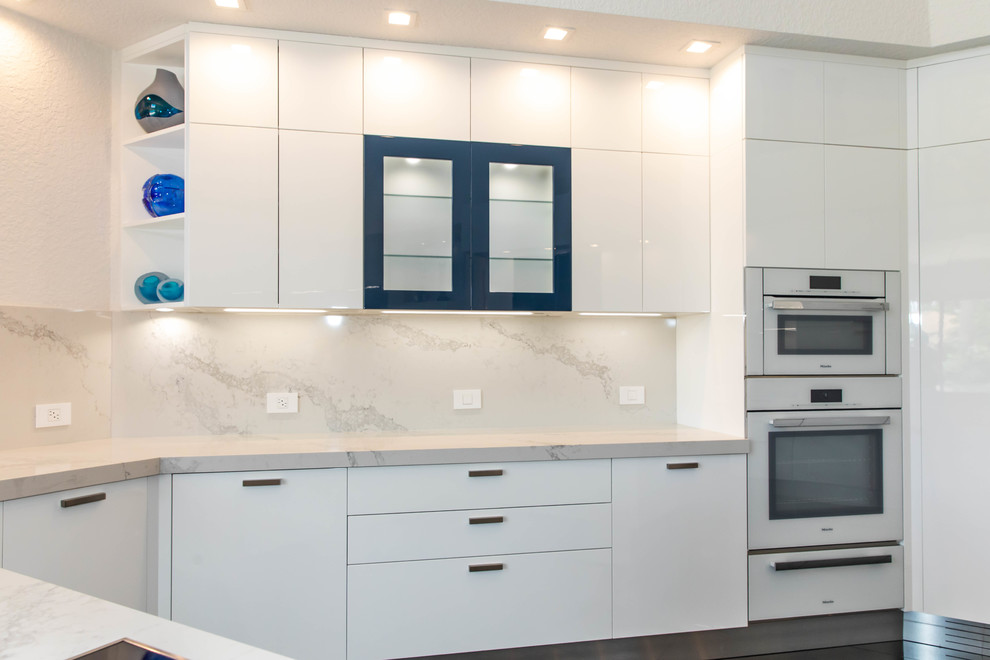 Design ideas for an expansive modern l-shaped eat-in kitchen in Miami with an undermount sink, flat-panel cabinets, white cabinets, quartz benchtops, multi-coloured splashback, stone slab splashback, white appliances, marble floors, with island, black floor and multi-coloured benchtop.