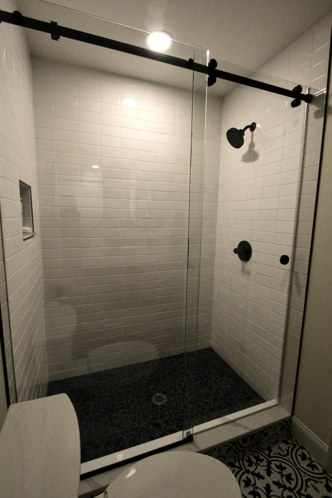 Réalisation d'une salle d'eau champêtre de taille moyenne avec une douche double, WC séparés, un carrelage blanc, un carrelage métro, un mur blanc, un sol en carrelage de céramique, un sol noir et une cabine de douche à porte coulissante.