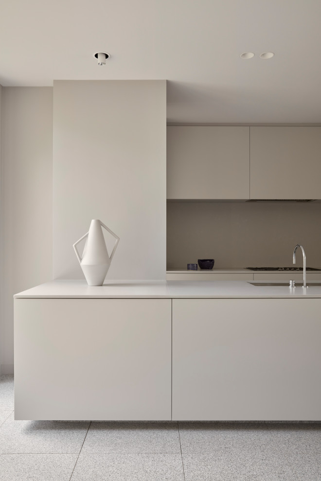 Стильный дизайн: кухня-гостиная среднего размера в стиле модернизм с бежевыми фасадами, бежевым фартуком, серым полом и бежевой столешницей - последний тренд