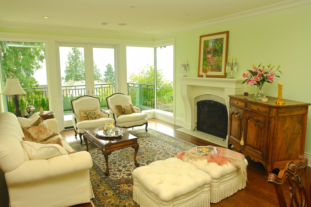 Photo of a mid-sized traditional formal open concept living room in Vancouver with green walls, medium hardwood floors, a standard fireplace, a stone fireplace surround and a concealed tv.