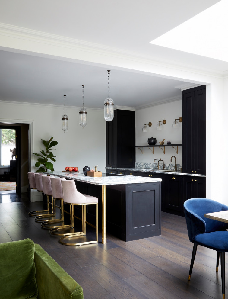 Design ideas for a large contemporary kitchen/diner in London with recessed-panel cabinets, black cabinets, marble worktops, white splashback, marble splashback, integrated appliances, dark hardwood flooring, an island, brown floors and white worktops.
