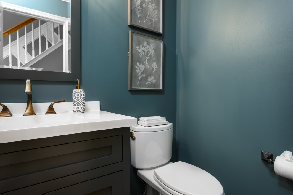 Inspiration för små klassiska vitt toaletter, med släta luckor, grå skåp, en toalettstol med separat cisternkåpa, blå väggar, ljust trägolv, ett integrerad handfat, bänkskiva i akrylsten och brunt golv