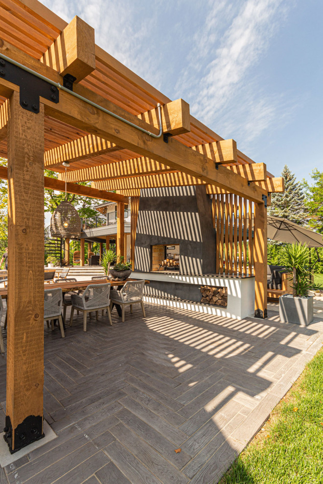 Photo of an expansive patio in Detroit with an outdoor kitchen, concrete pavers and a pergola.