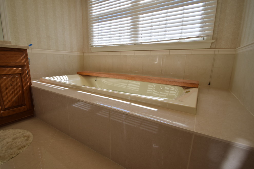 Drop-in bathtub - mid-sized transitional master beige tile and porcelain tile porcelain tile and gray floor drop-in bathtub idea with raised-panel cabinets, medium tone wood cabinets, a one-piece toilet, blue walls, an undermount sink, marble countertops and multicolored countertops