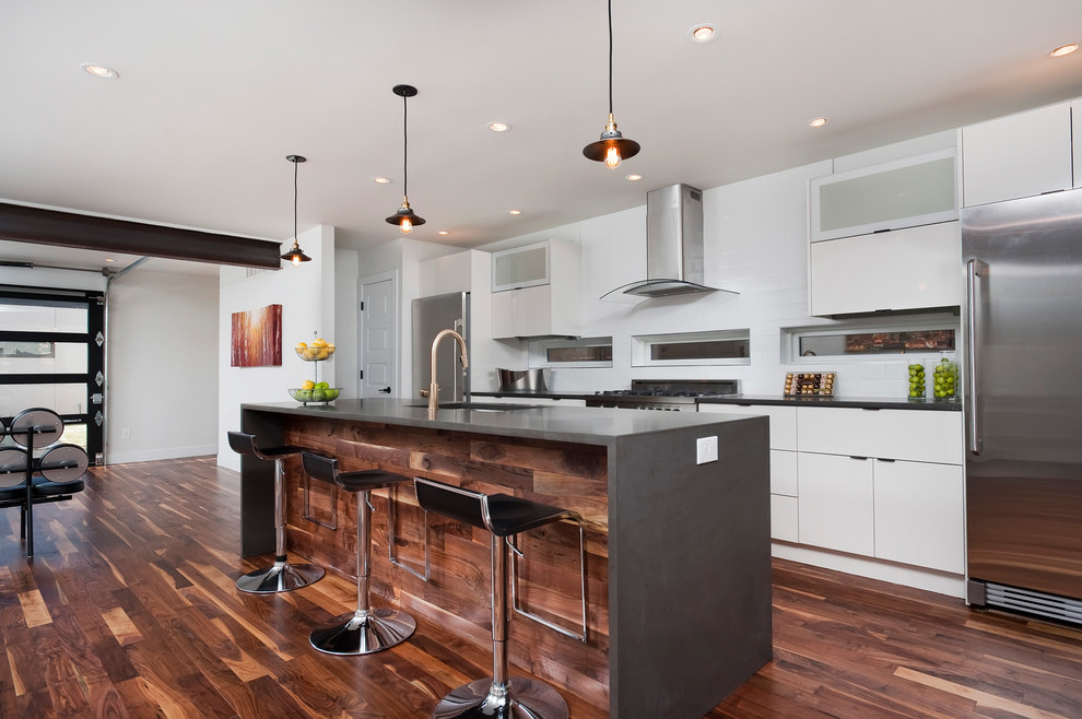 Photo of a contemporary galley kitchen in Denver with an undermount sink, flat-panel cabinets, white cabinets, stainless steel appliances, medium hardwood floors and with island.