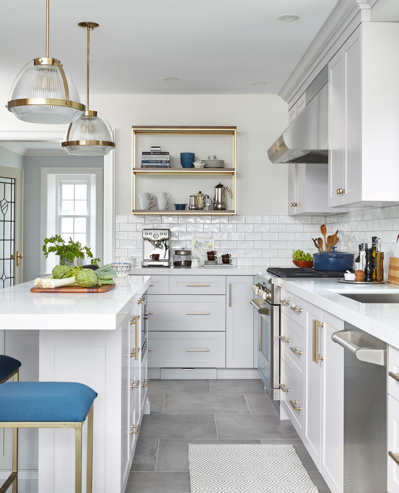 Inspiration for a transitional l-shaped kitchen in Toronto with an undermount sink, shaker cabinets, grey cabinets, white splashback, subway tile splashback, stainless steel appliances, with island and grey floor.