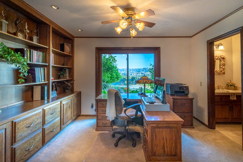 Design ideas for a mid-sized country home office in Los Angeles with a library, white walls, carpet, a freestanding desk and beige floor.