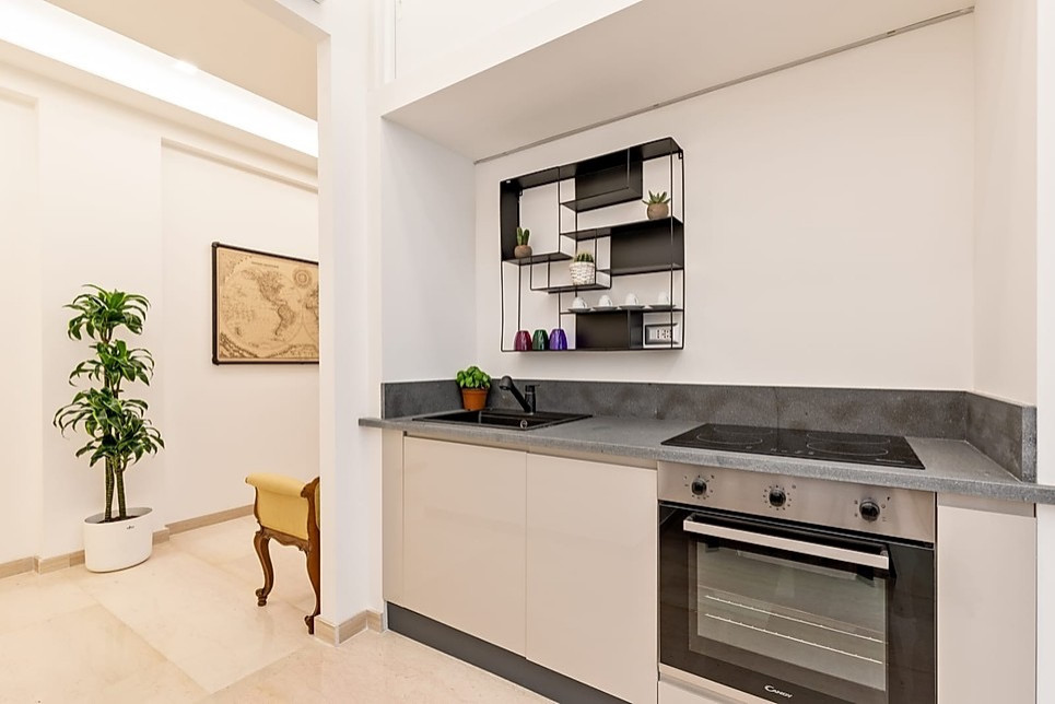 Small contemporary single-wall eat-in kitchen in Rome with beaded inset cabinets, grey cabinets, granite benchtops, grey splashback, granite splashback, black appliances, marble floors, no island, beige floor, grey benchtop and an undermount sink.