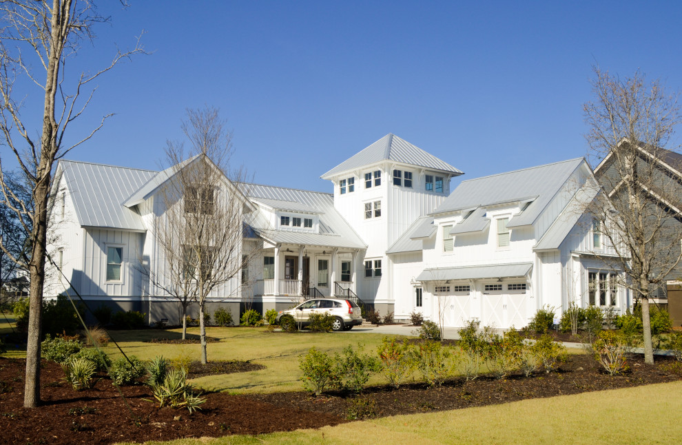 This is an example of a country two-storey white house exterior in Charleston with concrete fiberboard siding, a gable roof, a metal roof, a grey roof and board and batten siding.
