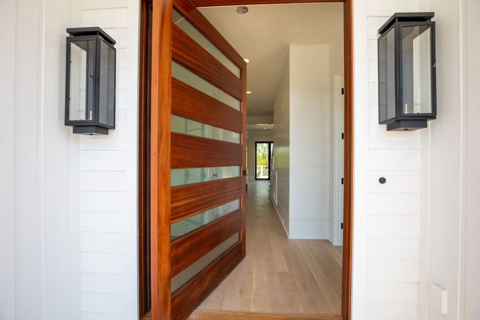 Idées déco pour une porte d'entrée avec un mur blanc, une porte pivot, une porte en bois brun et du lambris de bois.