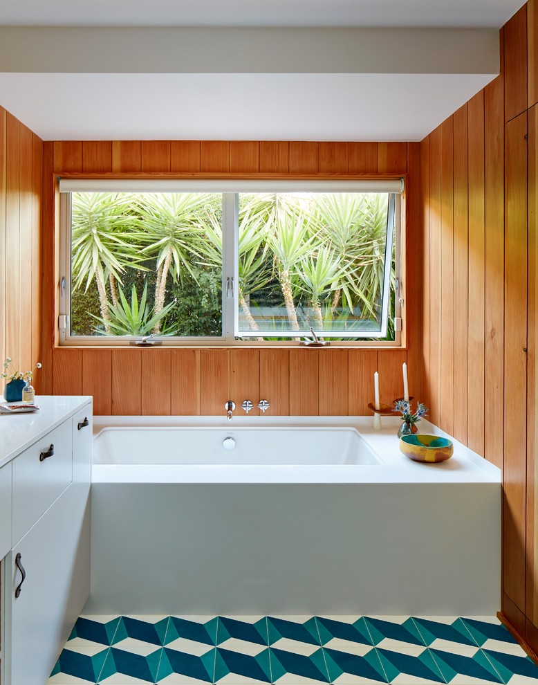 Midcentury master bathroom in Los Angeles with flat-panel cabinets, white cabinets, an undermount tub, brown walls, multi-coloured floor and white benchtops.
