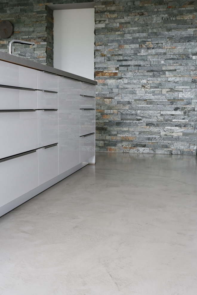 Expansive modern kitchen in Berlin with white cabinets, concrete benchtops, concrete floors, with island, grey floor and grey benchtop.