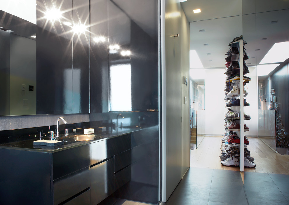 This is an example of a mid-sized modern men's walk-in wardrobe in New York with flat-panel cabinets and black floor.