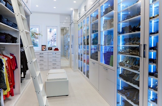 Large modern women's walk-in wardrobe in Tampa with glass-front cabinets, white cabinets and carpet.
