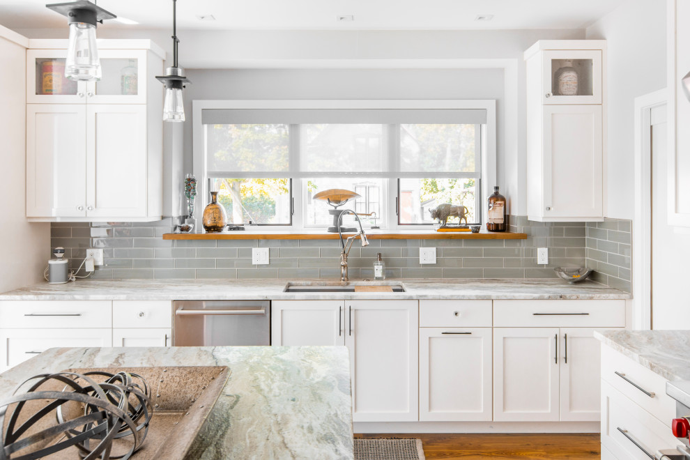 Design ideas for a transitional l-shaped kitchen in Detroit with an undermount sink, shaker cabinets, white cabinets, grey splashback, glass tile splashback, stainless steel appliances, medium hardwood floors, with island, brown floor and grey benchtop.