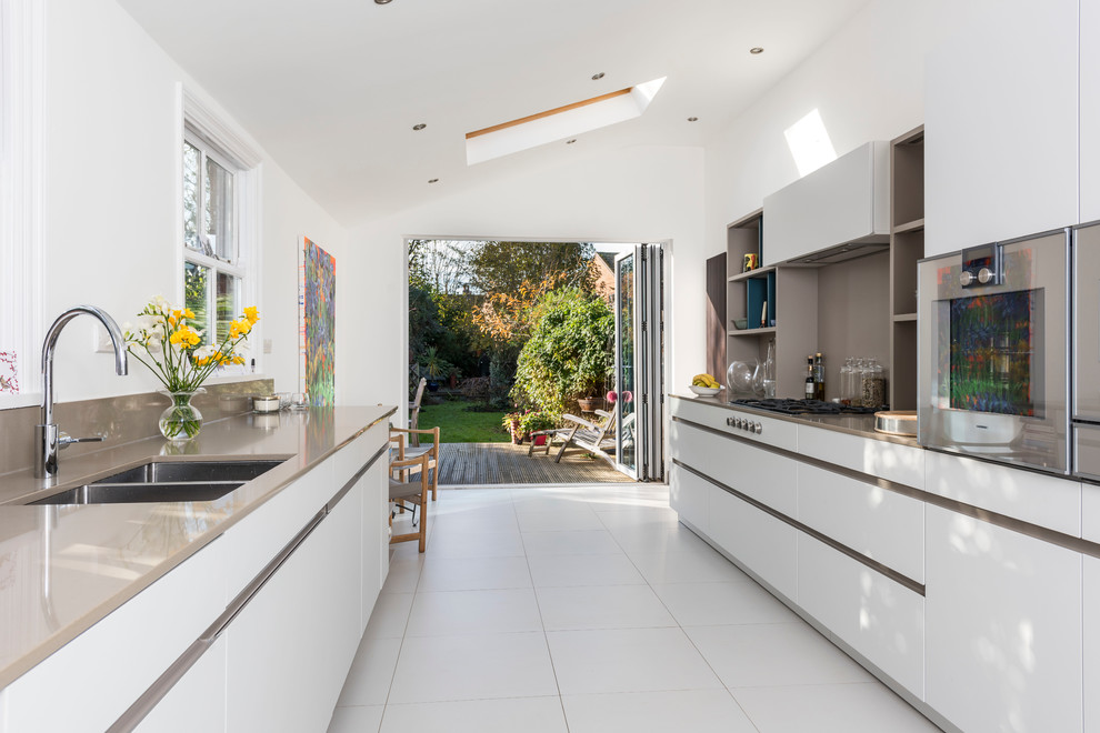 Design ideas for a large contemporary galley open plan kitchen in West Midlands with an undermount sink, flat-panel cabinets, brown splashback, stainless steel appliances and ceramic floors.