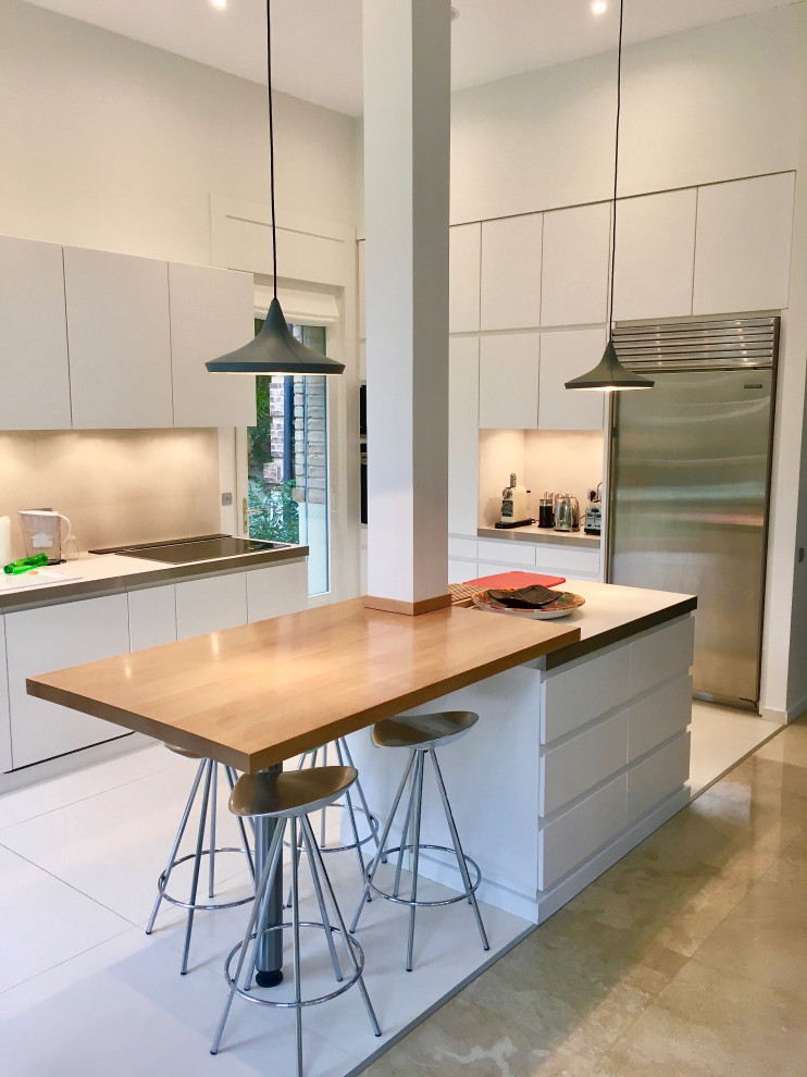 Стильный дизайн: огромная параллельная кухня-гостиная в стиле модернизм с плоскими фасадами, деревянной столешницей и островом - последний тренд
