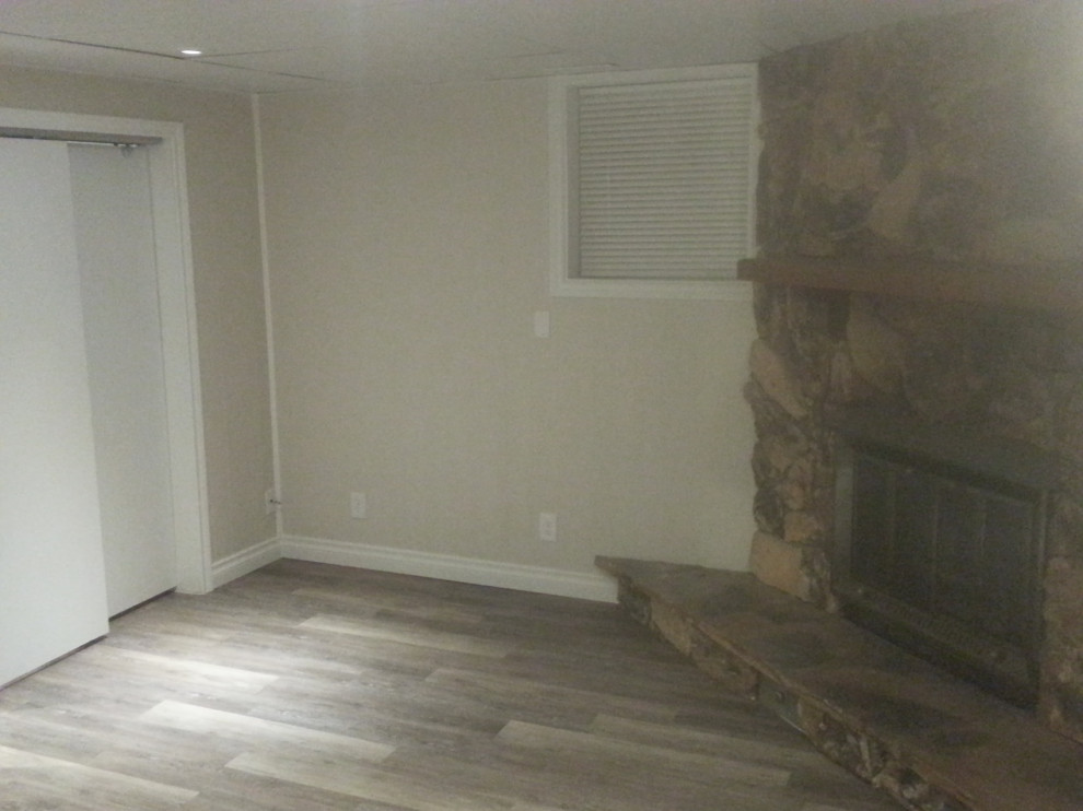 Imagen de dormitorio clásico renovado grande con suelo vinílico, chimenea de esquina, marco de chimenea de piedra y suelo marrón