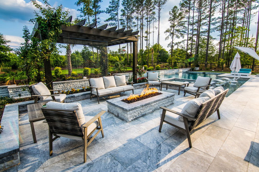 Large transitional backyard full sun garden in Raleigh with a fire feature and natural stone pavers.