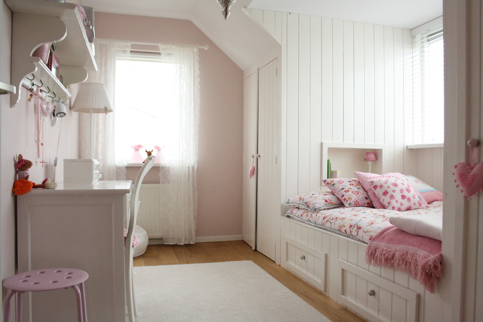 This is an example of a contemporary kids' bedroom for kids 4-10 years old and girls in Amsterdam with light hardwood floors and pink walls.