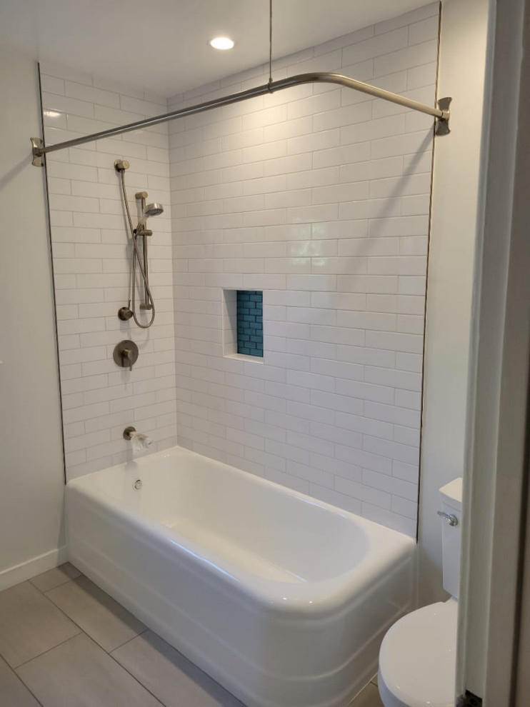 This is an example of a mid-sized traditional 3/4 bathroom in Los Angeles with flat-panel cabinets, white cabinets, a corner tub, a shower/bathtub combo, a one-piece toilet, white tile, porcelain tile, white walls, ceramic floors, an integrated sink, tile benchtops, grey floor, a shower curtain, white benchtops, a single vanity and a freestanding vanity.