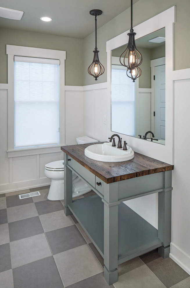 Design ideas for a large traditional powder room in Omaha with a drop-in sink, furniture-like cabinets, wood benchtops, a two-piece toilet, green walls, ceramic floors, blue cabinets, gray tile and brown benchtops.