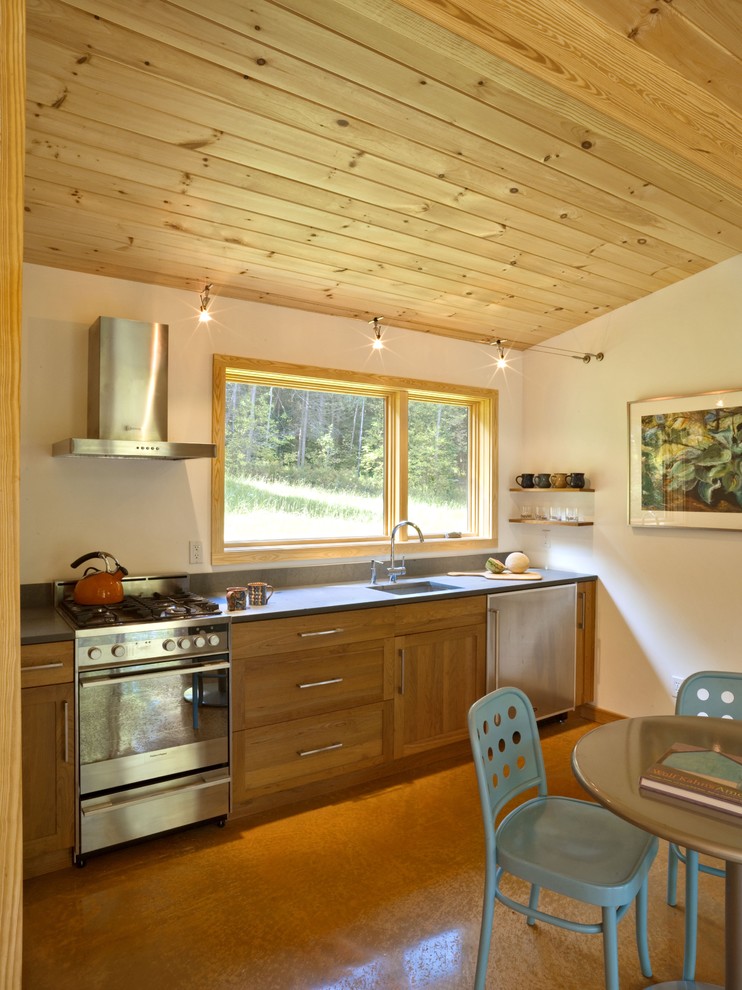 This is an example of a mid-sized modern single-wall eat-in kitchen in Burlington with stainless steel appliances, a single-bowl sink, medium wood cabinets, shaker cabinets, quartz benchtops, concrete floors, no island and brown floor.