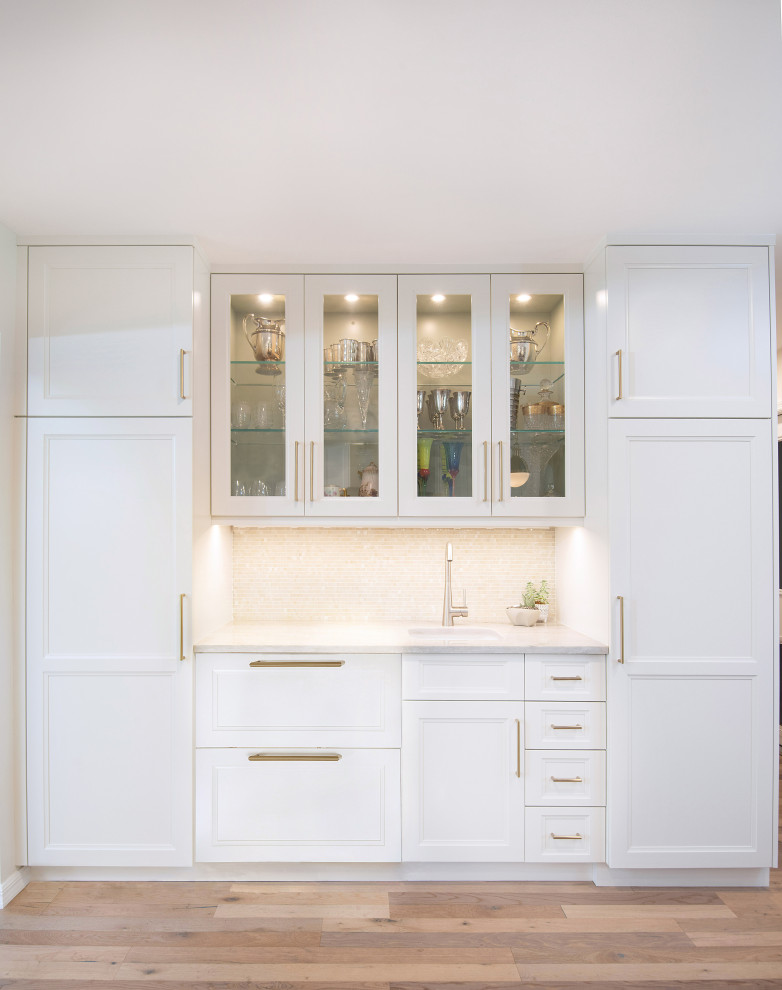 This is an example of a medium sized traditional galley wet bar in Miami with a submerged sink, recessed-panel cabinets, white cabinets, engineered stone countertops, white splashback, mosaic tiled splashback, medium hardwood flooring, beige floors and white worktops.