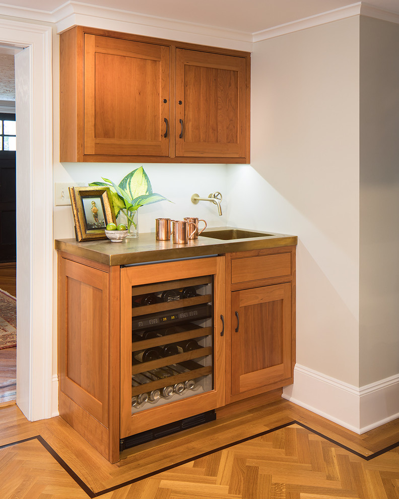 Inspiration for a small traditional l-shaped home bar in New York with shaker cabinets, brown cabinets, marble benchtops, green splashback, multi-coloured floor, an integrated sink and light hardwood floors.