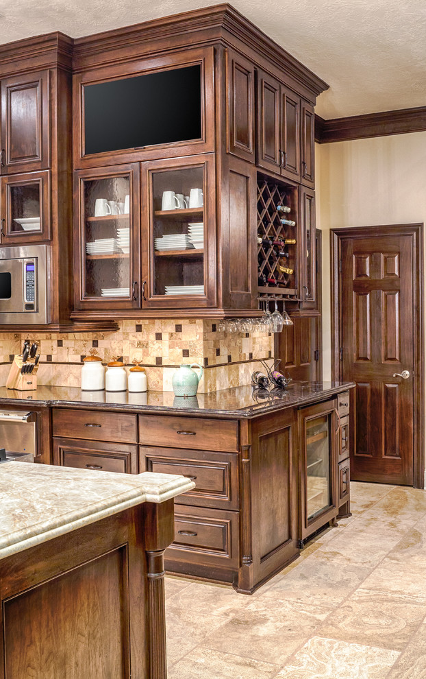 Design ideas for a large traditional u-shaped eat-in kitchen in Houston with an undermount sink, raised-panel cabinets, dark wood cabinets, granite benchtops, beige splashback, stone tile splashback, panelled appliances, travertine floors and with island.