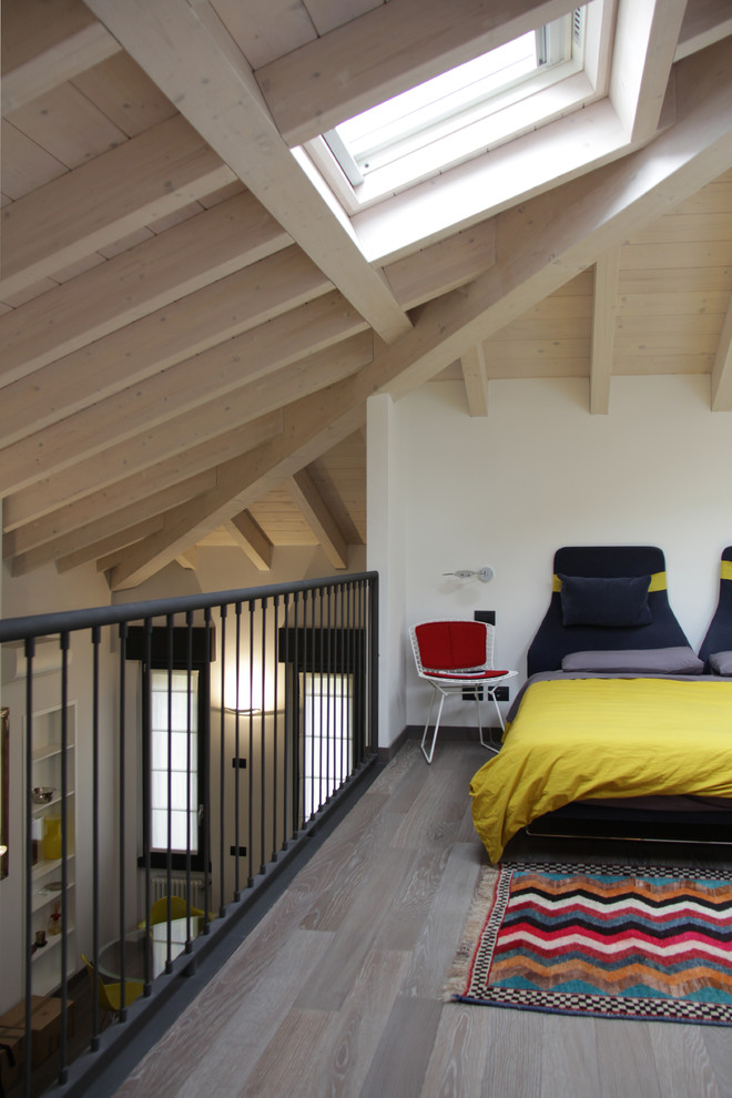 This is an example of an expansive contemporary loft-style bedroom in Milan with white walls and medium hardwood floors.