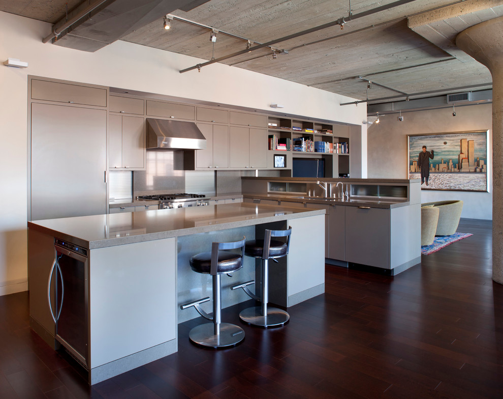 Inspiration for a small industrial l-shaped eat-in kitchen in San Francisco with a drop-in sink, flat-panel cabinets, grey cabinets, quartz benchtops, grey splashback, stone tile splashback, stainless steel appliances, dark hardwood floors and with island.