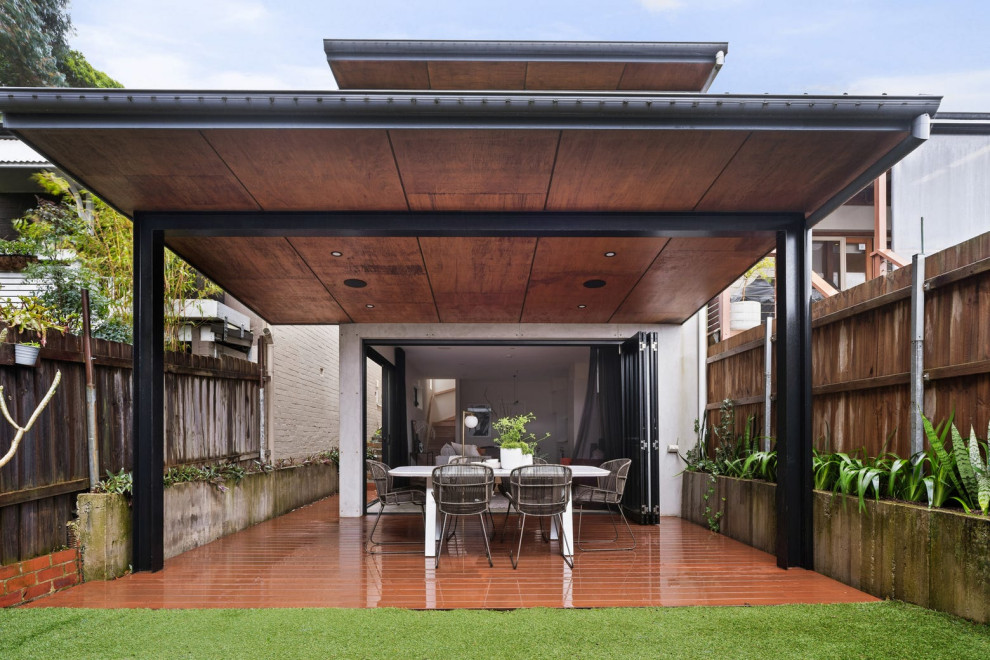 Idées déco pour un petit porche d'entrée de maison arrière moderne avec des colonnes, une terrasse en bois et une extension de toiture.