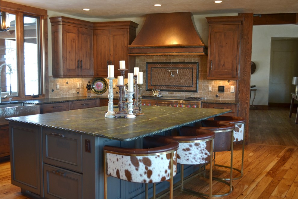 Inspiration for a large rustic u-shaped light wood floor and brown floor enclosed kitchen remodel in Denver with a farmhouse sink, recessed-panel cabinets, medium tone wood cabinets, granite countertops, beige backsplash, stone tile backsplash, stainless steel appliances and an island