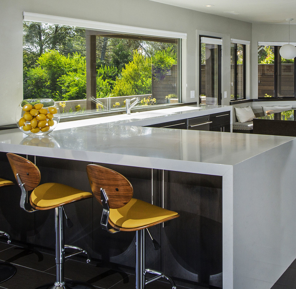 This is an example of a large contemporary u-shaped open plan kitchen in San Diego with an undermount sink, flat-panel cabinets, glass benchtops, beige splashback, stainless steel appliances, porcelain floors, multiple islands and black cabinets.