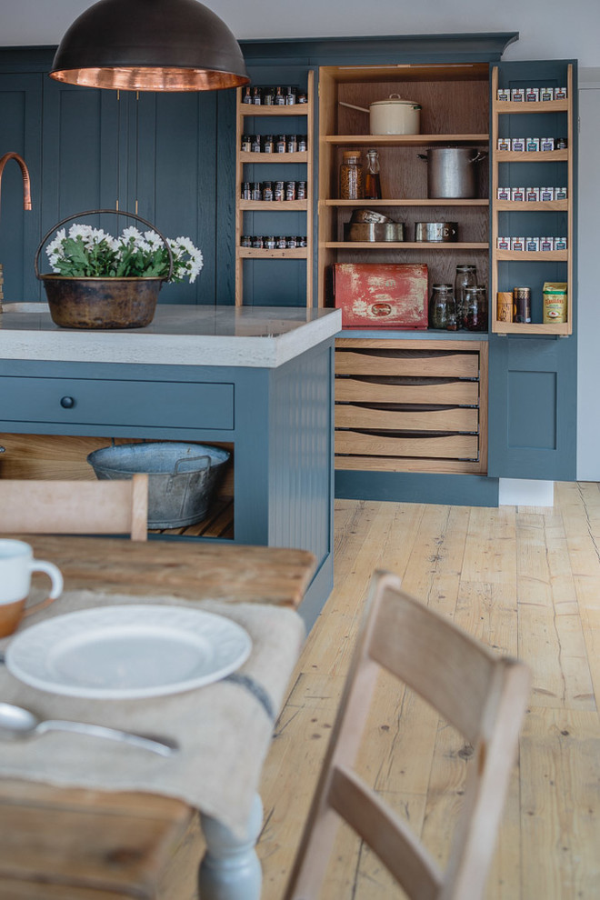 Photo of a mid-sized industrial l-shaped eat-in kitchen in Other with a farmhouse sink, shaker cabinets, grey cabinets, concrete benchtops, light hardwood floors and with island.