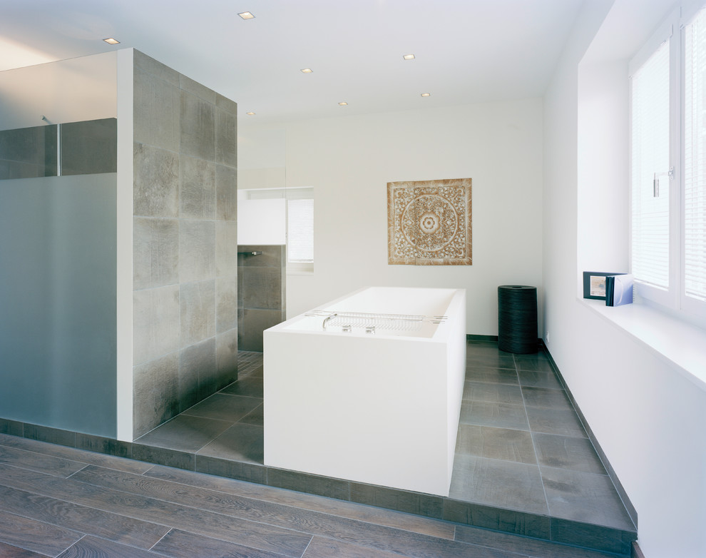 Large modern bathroom in Other with a freestanding tub, brown tile, stone tile, white walls and an open shower.