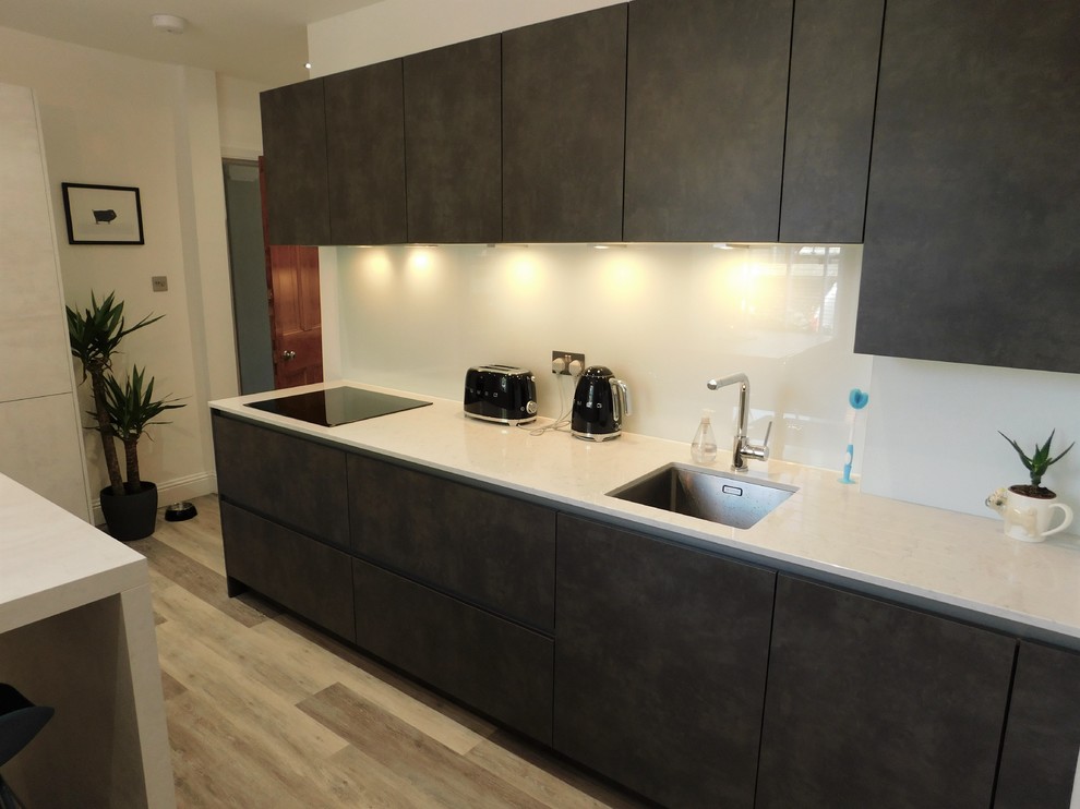 Photo of a mid-sized contemporary kitchen in Edinburgh with an undermount sink, flat-panel cabinets, quartzite benchtops, white splashback, glass sheet splashback, panelled appliances, vinyl floors and with island.