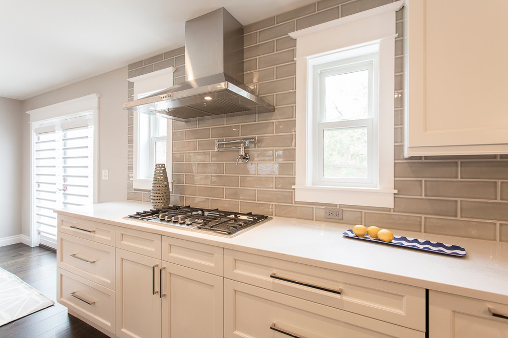 Inspiration for a large transitional l-shaped medium tone wood floor and brown floor eat-in kitchen remodel in Denver with a single-bowl sink, recessed-panel cabinets, white cabinets, quartz countertops, gray backsplash, ceramic backsplash, stainless steel appliances and two islands