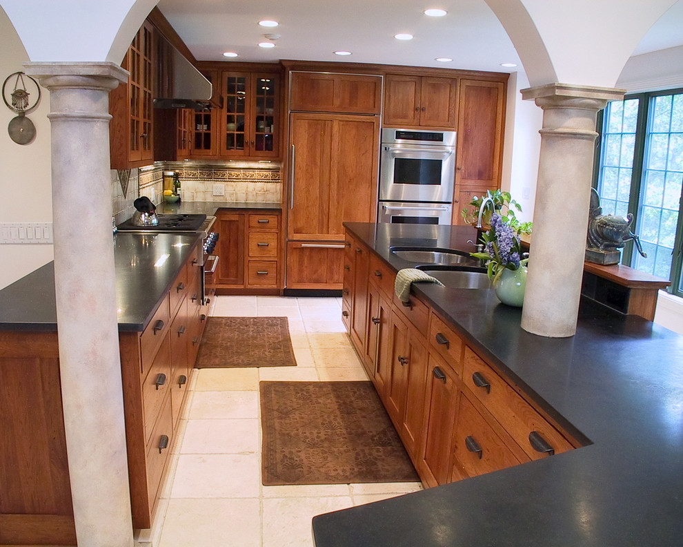 Photo of a mediterranean kitchen in Boston with glass-front cabinets, a double-bowl sink, medium wood cabinets, granite benchtops and panelled appliances.