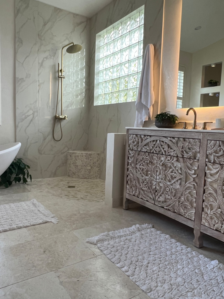 Design ideas for a mid-sized mediterranean master bathroom in Miami with grey cabinets, a freestanding tub, an open shower, a two-piece toilet, gray tile, pebble tile, beige walls, travertine floors, an undermount sink, quartzite benchtops, white floor, an open shower, beige benchtops, a shower seat, a double vanity, a freestanding vanity and vaulted.