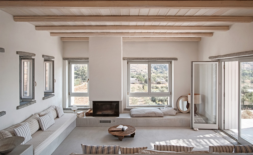 Photo of a mediterranean formal enclosed living room in Barcelona with white walls, concrete floors, a standard fireplace, a plaster fireplace surround, no tv and grey floor.
