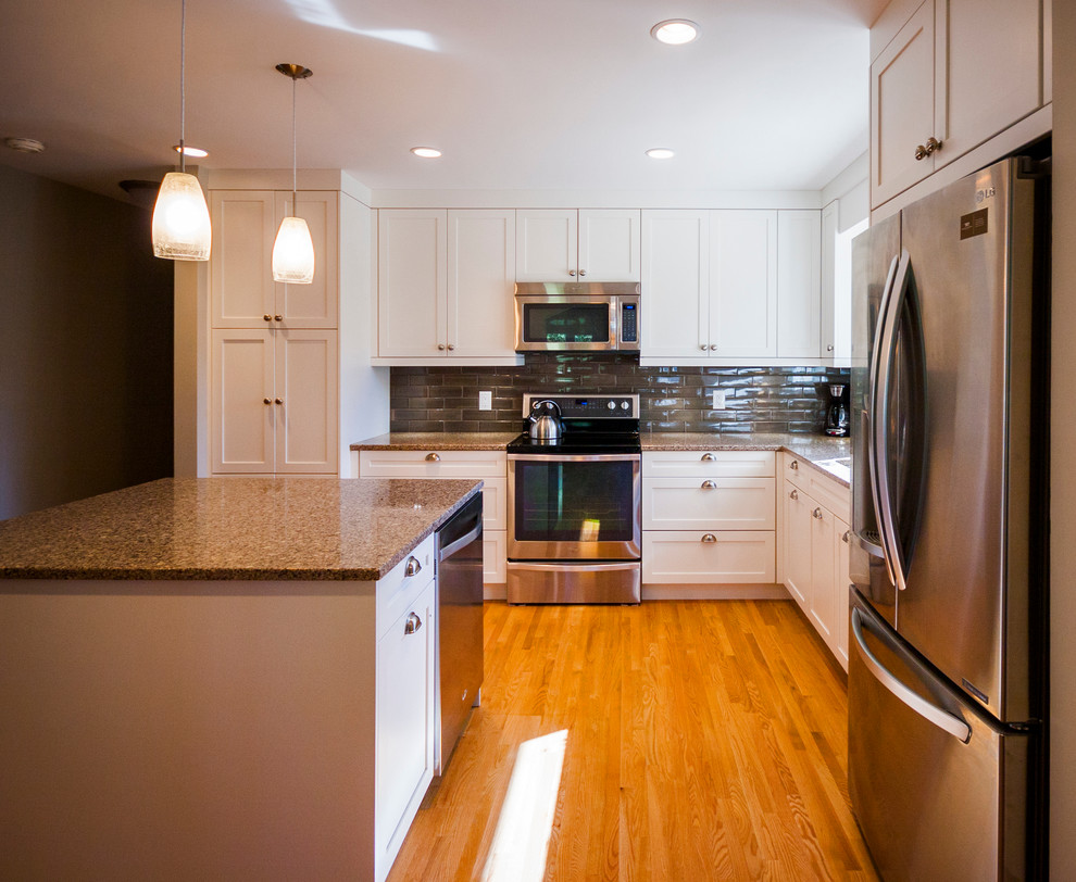 Inspiration for a mid-sized transitional l-shaped light wood floor eat-in kitchen remodel with a double-bowl sink, shaker cabinets, white cabinets, quartz countertops, brown backsplash, ceramic backsplash, stainless steel appliances and an island