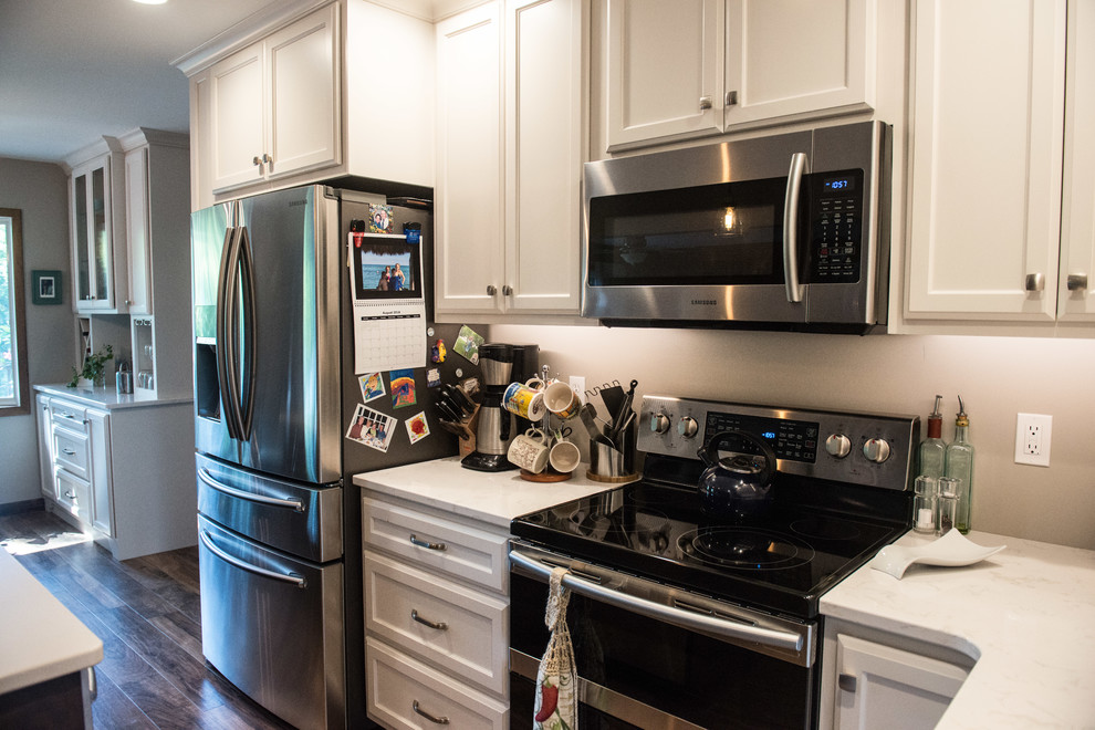 Open concept kitchen - large transitional l-shaped medium tone wood floor open concept kitchen idea with a double-bowl sink, flat-panel cabinets, white cabinets, quartz countertops, gray backsplash, stainless steel appliances, an island and white countertops