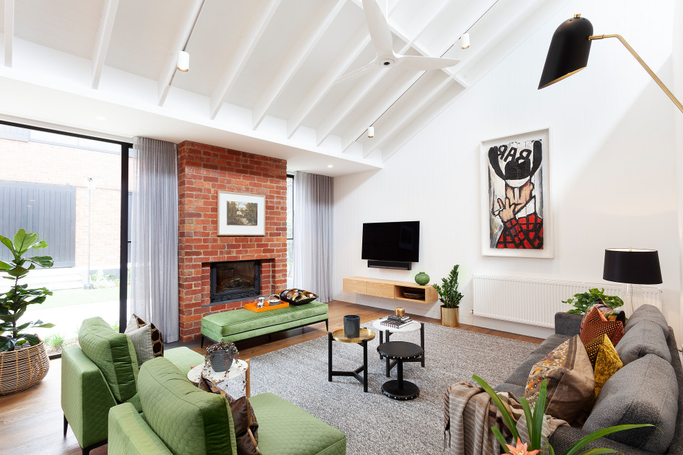 Inspiration for a contemporary open concept living room in Melbourne with white walls, medium hardwood floors, a standard fireplace, a brick fireplace surround, a wall-mounted tv, exposed beam and vaulted.