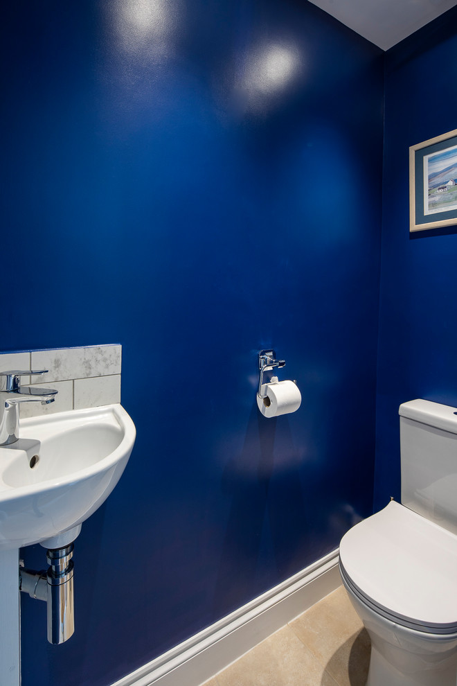 This is an example of a small traditional powder room in London with blue walls, ceramic floors, a pedestal sink, beige floor and white benchtops.